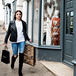 Woman with shopping bags walking past shops on a street